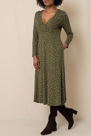 A model wearing the Rose Dress in colour Olive (Green), from the front, cropped image