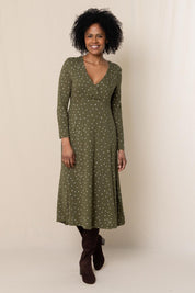 A model wearing the Rose Dress in colour Olive (Green), from the front, showing the whole outfit