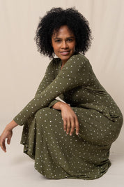 A model wearing the Rose Dress in colour Olive (Green), from the front, showing the whole outfit