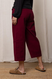 A model wearing the Charlie Cotton Canvas Trouser in colour Mulberry (Red), from the back