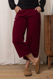 A model wearing the Charlie Cotton Canvas Trouser in colour Mulberry (Red), from the front, cropped image