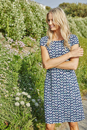 A model wearing the Harbourside Dress in colour Petlgeomet (Blue), from the front, showing the whole outfit