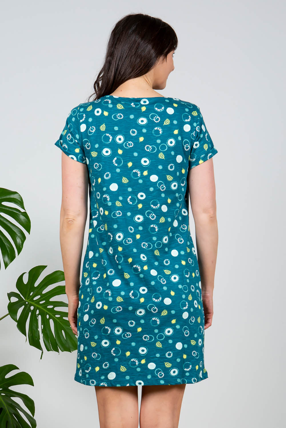 A model wearing the Heather Dress in colour Darkteal (Green), from the back