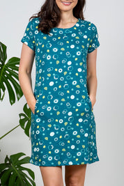 A model wearing the Heather Dress in colour Darkteal (Green), from the front, cropped image
