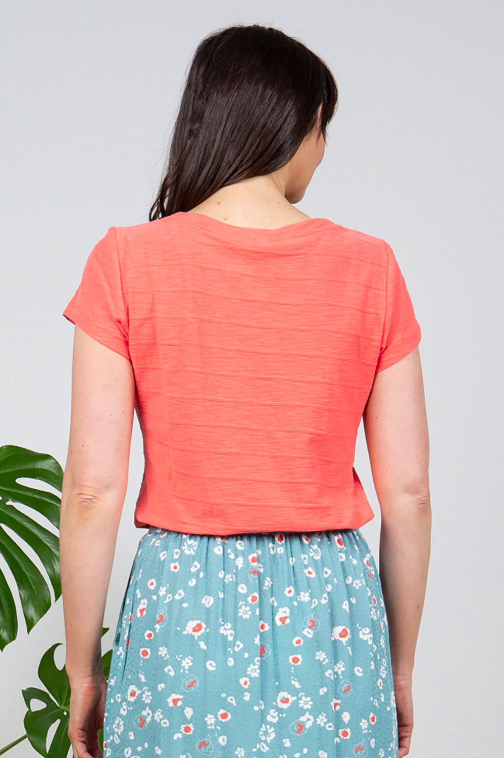 A model wearing the Cockles Tee in colour Papaya (Pink), from the back