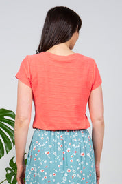 A model wearing the Cockles Tee in colour Papaya (Pink), from the back