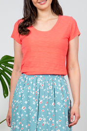 A model wearing the Cockles Tee in colour Papaya (Pink), from the front, cropped image