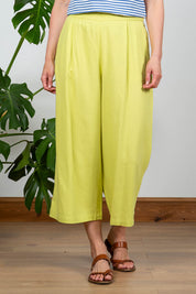 A model wearing the Summer Trouser in colour Citron, from the front, cropped image