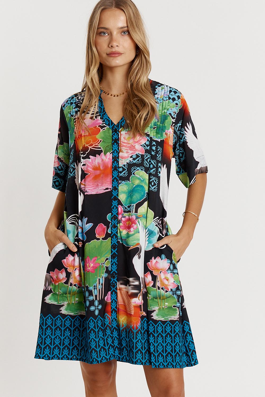 A model wearing the Akiko Button Dress in colour Ocean (Blue), from the front, cropped image
