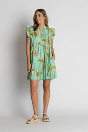 A model wearing the Badira Cotton Ruffle Dress in colour Mist (Green), from the front, showing the whole outfit