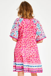 Model Naomi wearing size S of the Jordan Shirred Dress in colour Melon (Pink), from the back