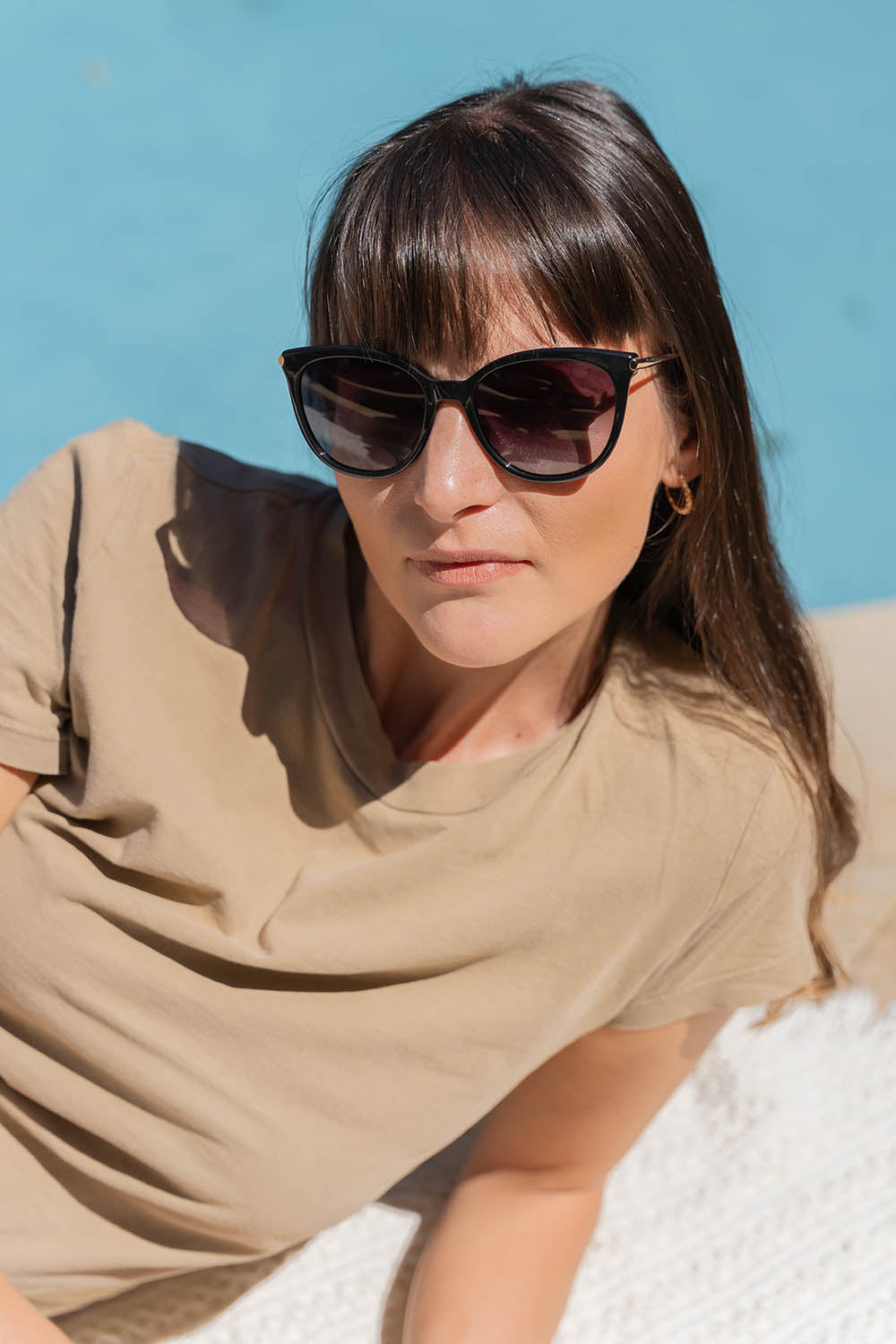 A model wearing the Ashley Sunglasses in colour Black (Black), from the front, showing the whole outfit