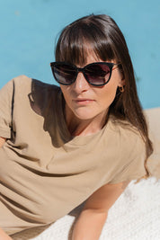 A model wearing the Ashley Sunglasses in colour Black (Black), from the front, showing the whole outfit