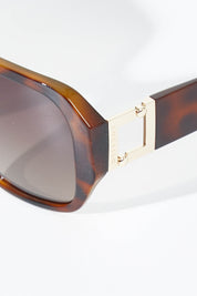 A model wearing size OneSize of the Bessie Sunglasses in colour Tortoise, from the front, showing the whole outfit