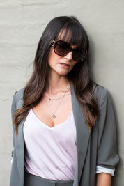 A model wearing the Bessie Sunglasses in colour Tortoise, from the front, showing the whole outfit