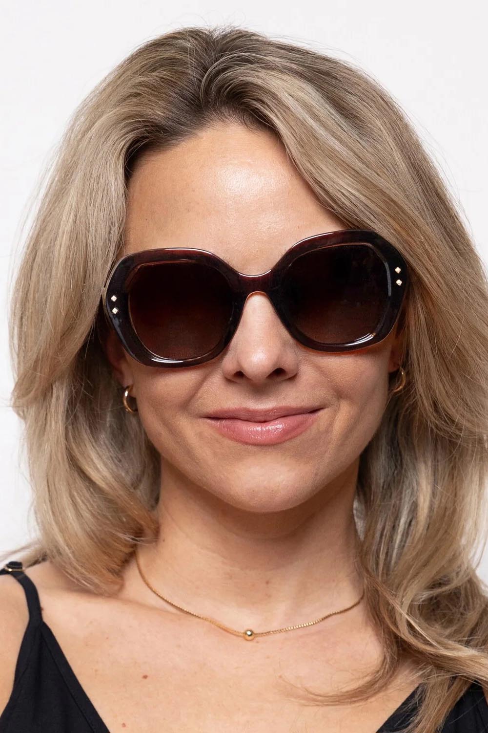 A model wearing the Kamilla Sunglasses in colour Crystbrown, from the front, cropped image