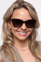 A model wearing the Layla Sunglasses in colour Crystbrown, from the front, cropped image