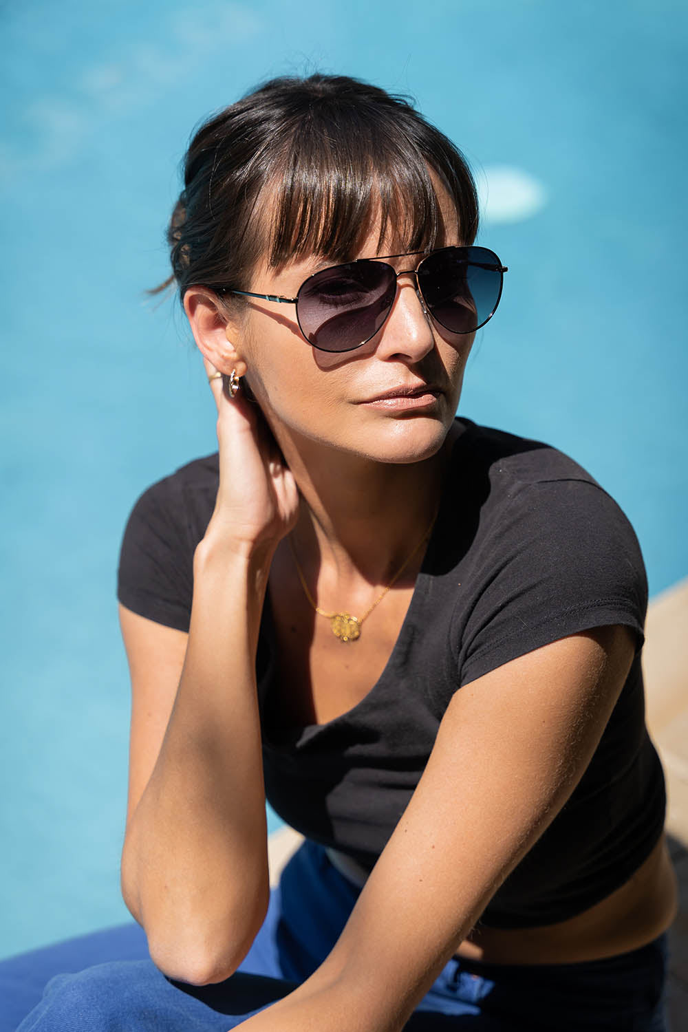 A model wearing the Mara Sunglasses in colour Black (Black), from the front, showing the whole outfit