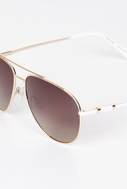 A model wearing size OneSize of the Mara Sunglasses in colour Gold (Metallics), from the front, showing the whole outfit