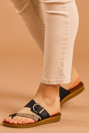 A model wearing size 38 of the Bria Flat Sandal in colour Black (Black), from the front, cropped image