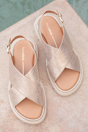 A model wearing the Tolis Flatform Sandal in colour Beigelizar (Metallics), from the front, showing the whole outfit