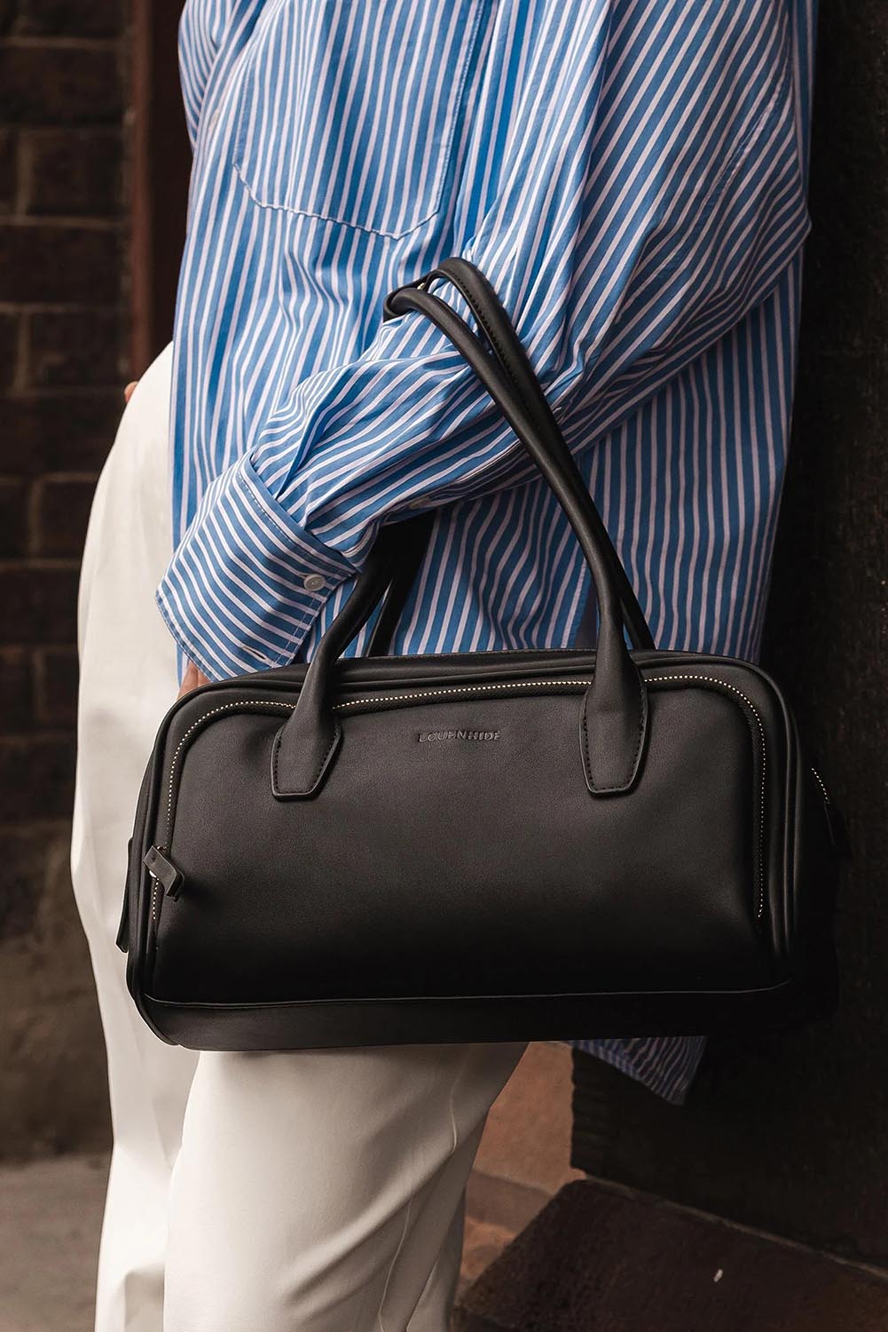 A model wearing the Paloma Shoulder Bag in colour Black (Black), from the front, showing the whole outfit