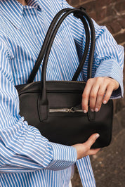 A model wearing the Paloma Shoulder Bag in colour Black (Black), from the front, showing the whole outfit