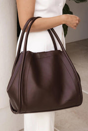 A model wearing the Sutton Shoulder Bag in colour Chocolate, from the front, showing the whole outfit