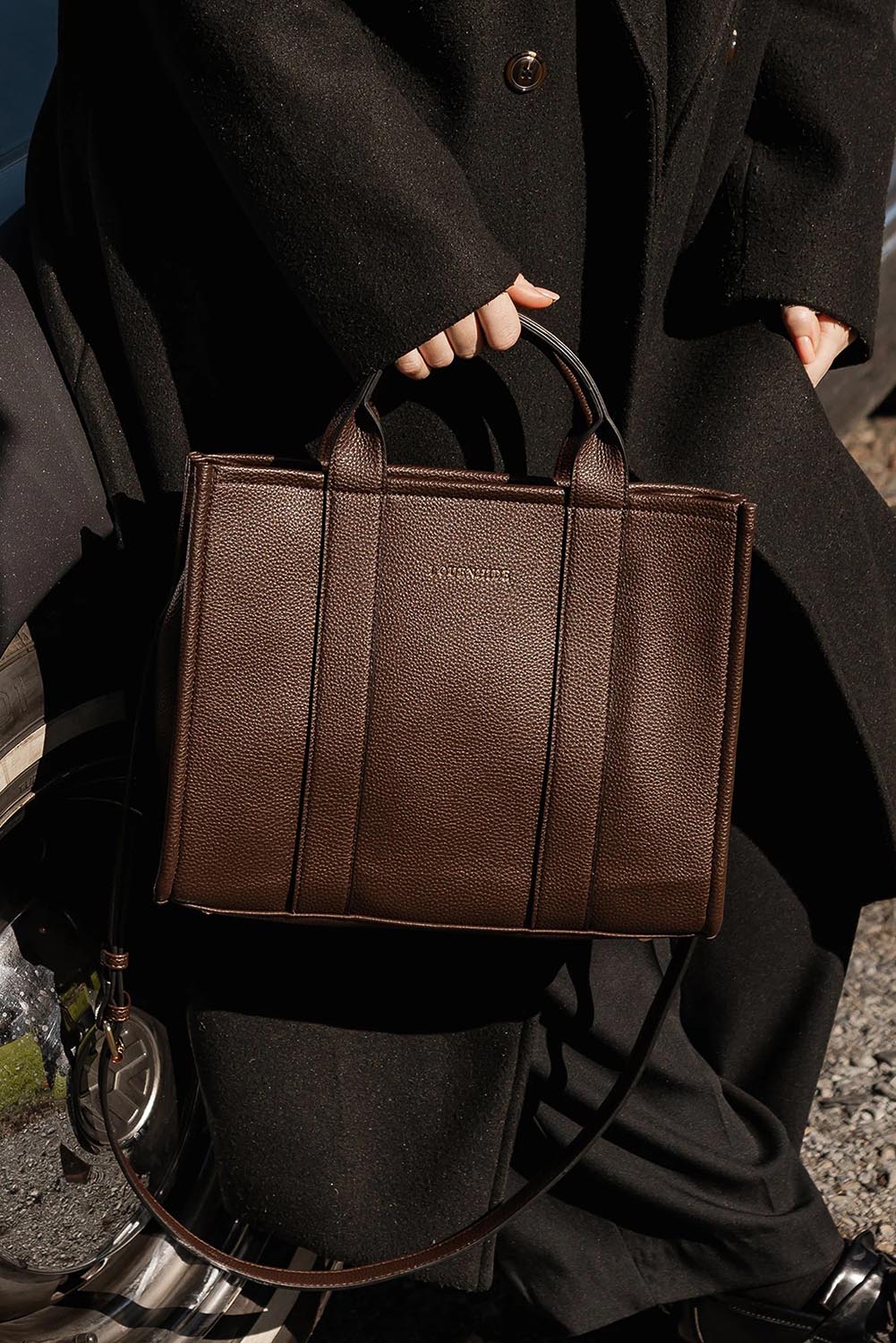 A model wearing the Manhattan Tote Bag in colour Chocolate, from the front, showing the whole outfit