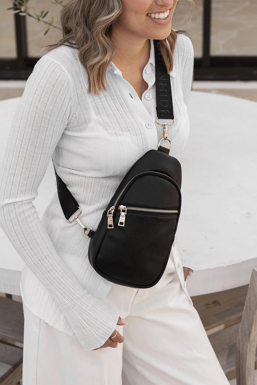 A model wearing the Bella Sling Bag in colour Black (Black), from the front, showing the whole outfit