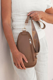 A model wearing the Bella Sling Bag in colour Caramel, from the front, showing the whole outfit
