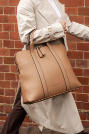 A model wearing the Rhodes Laptop Bag in colour Latte, from the front, showing the whole outfit