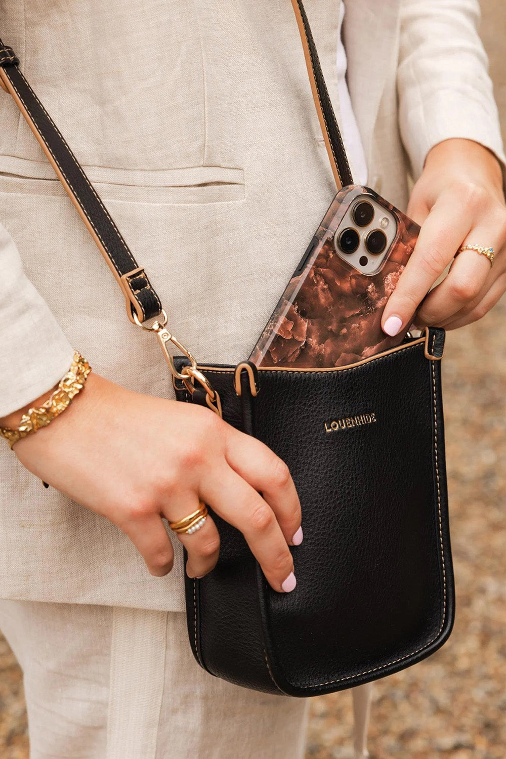 A model wearing the Parker Phone Crossbody Bag in colour Black (Black), from the front, showing the whole outfit