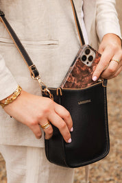 A model wearing the Parker Phone Crossbody Bag in colour Black (Black), from the front, showing the whole outfit