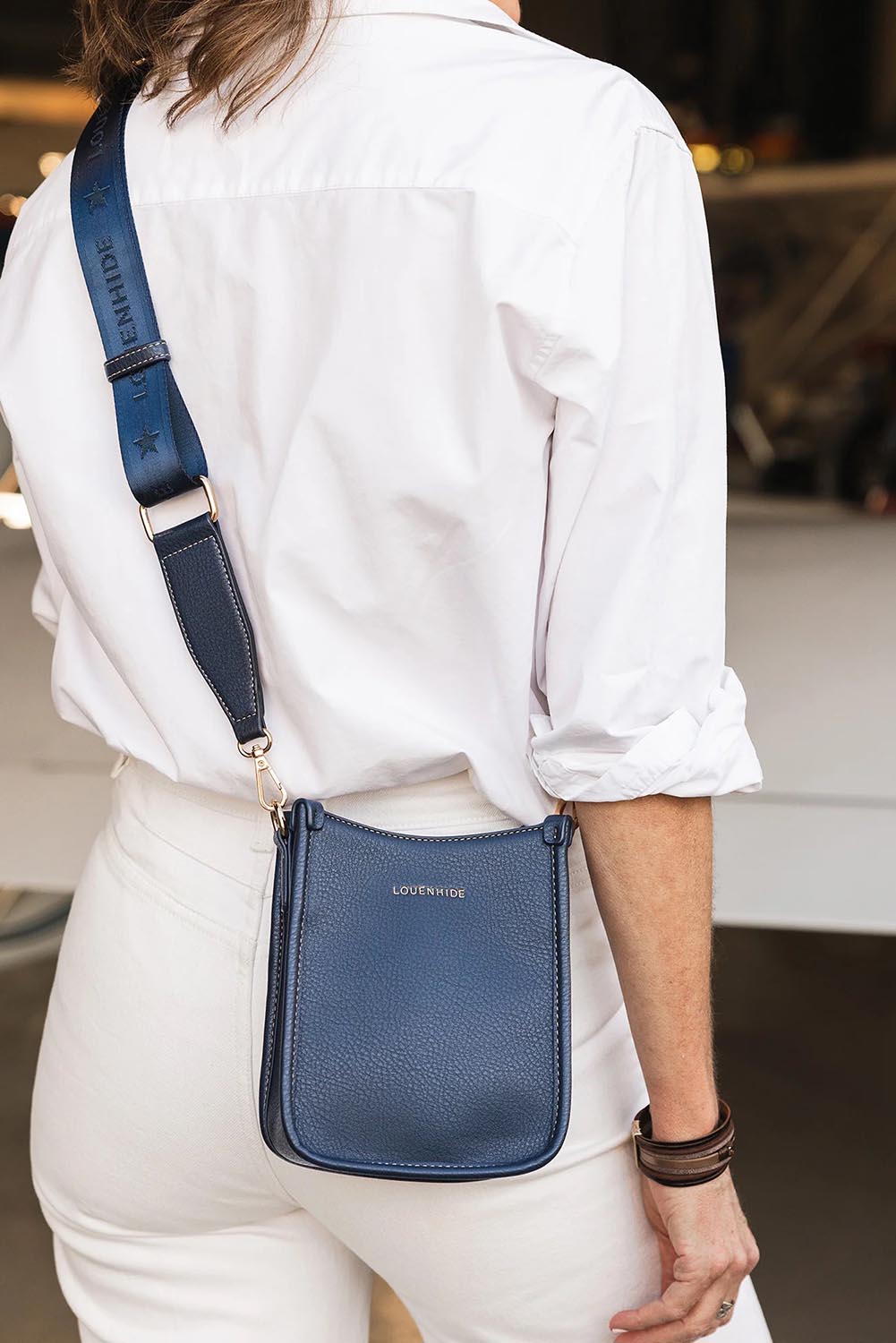 A model wearing the Parker Phone Crossbody Bag in colour Navy (Blue), from the front, showing the whole outfit