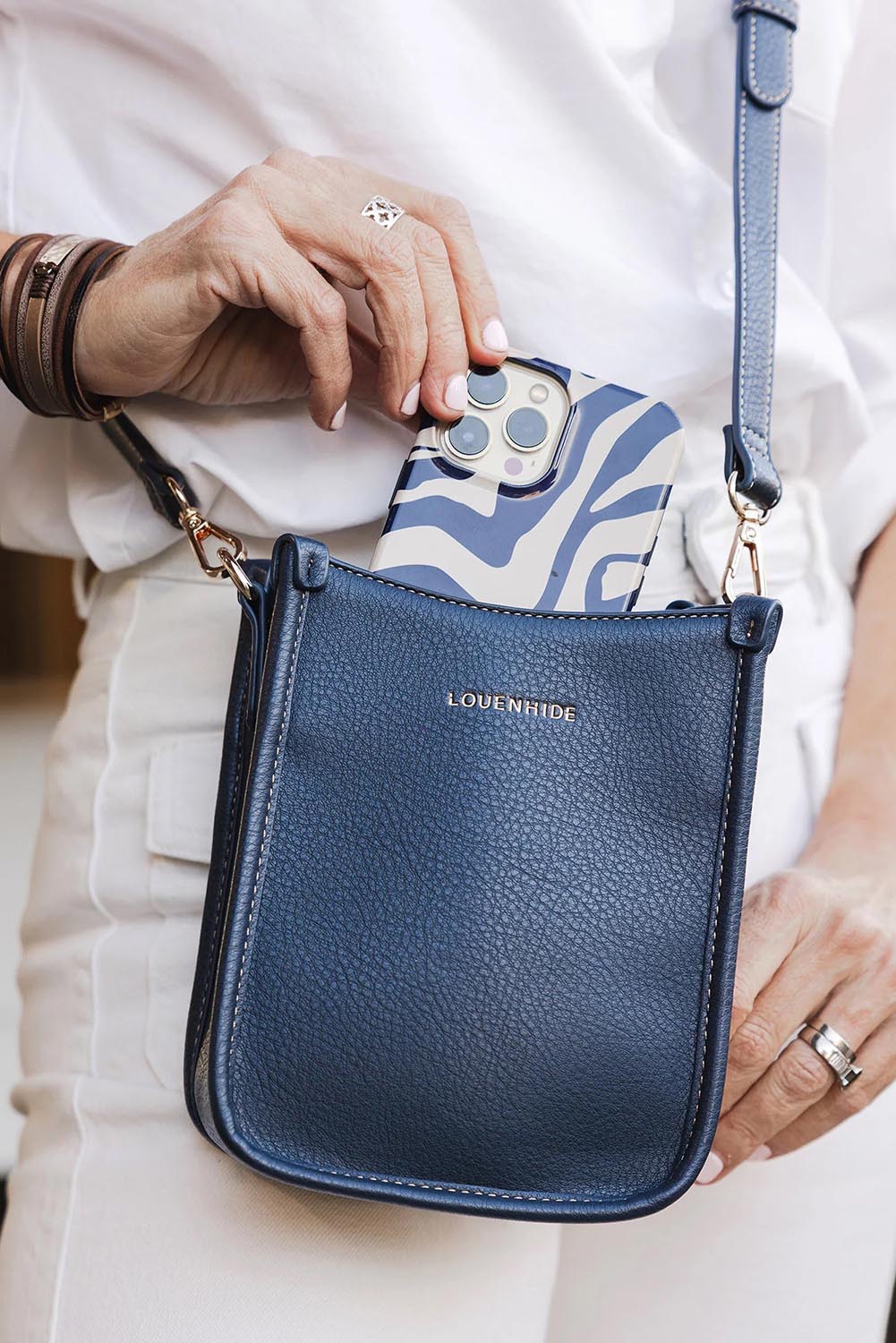 A model wearing the Parker Phone Crossbody Bag in colour Navy (Blue), from the front, showing the whole outfit
