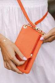 A model wearing the Billie Crossbody Phone Bag in colour Orange, from the front, showing the whole outfit