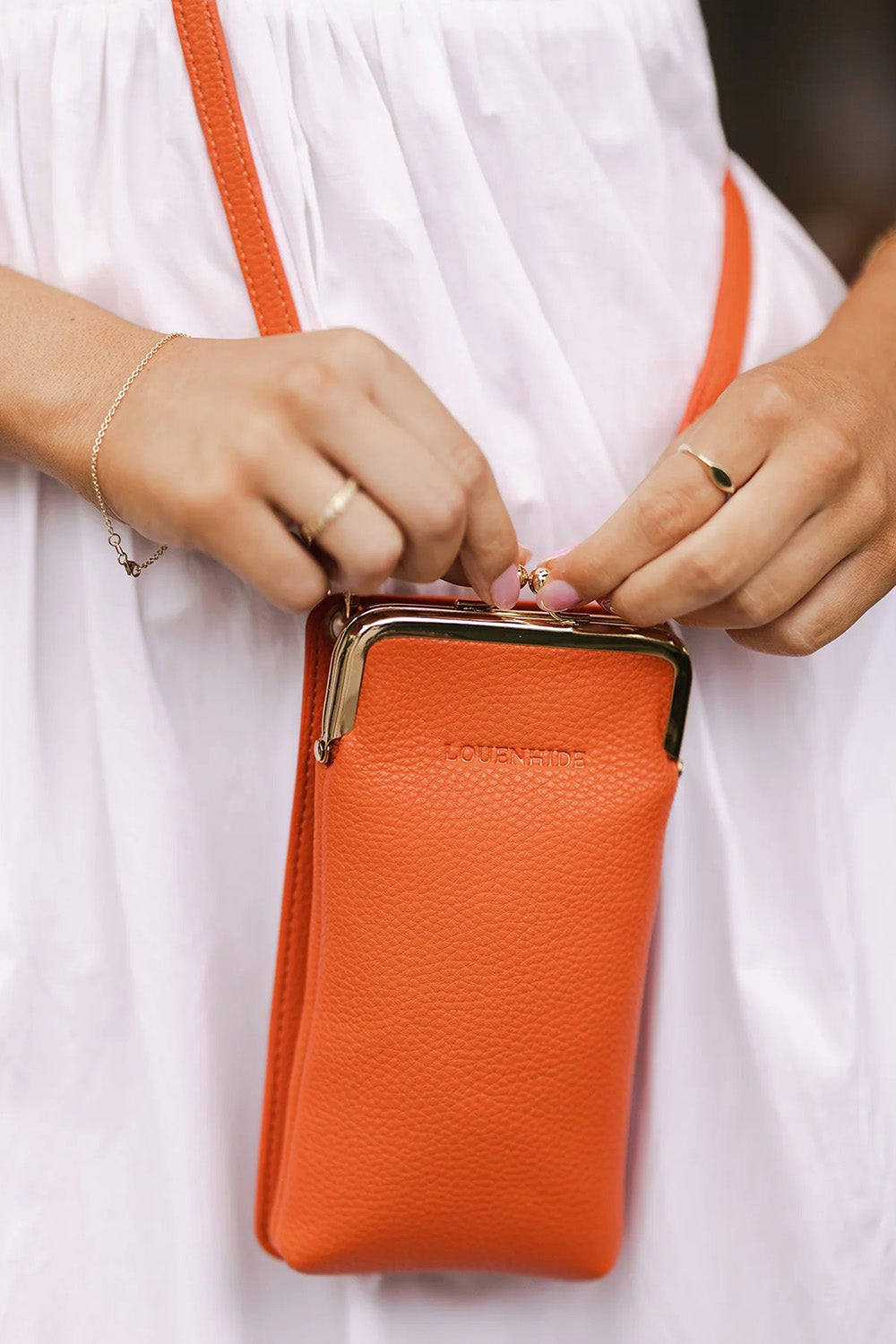 A model wearing the Billie Crossbody Phone Bag in colour Orange, from the front, showing the whole outfit