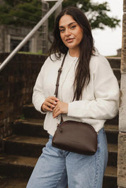 A model wearing the Alison Crossbody Handbag in colour Chocolate, from the front, showing the whole outfit
