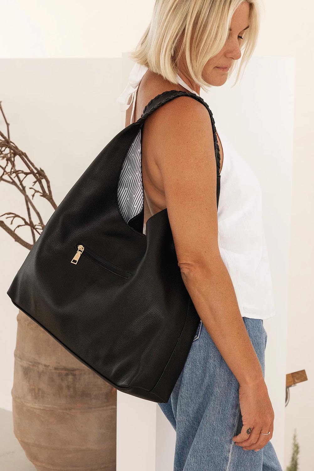 A model wearing the Avery Shoulder Bag in colour Black (Black), from the front, showing the whole outfit