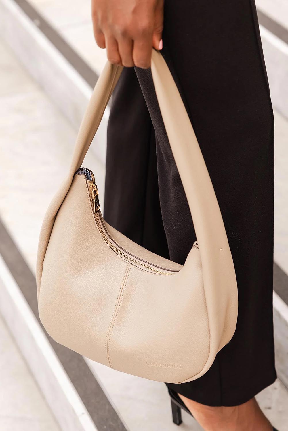 A model wearing the Capri Shoulder Bag in colour Stone, from the front, showing the whole outfit