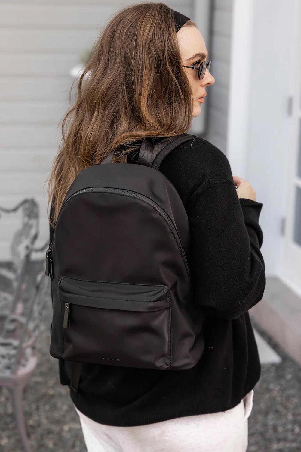 A model wearing the Carter Backpack in colour Black (Black), from the front, showing the whole outfit
