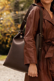 A model wearing the Audrey Shoulder Bag in colour Chocolate, from the front, showing the whole outfit
