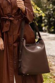 A model wearing the Audrey Shoulder Bag in colour Chocolate, from the front, showing the whole outfit