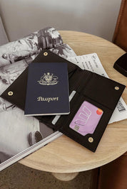 A model wearing the Venice Passport Wallet in colour Black (Black), from the front, showing the whole outfit