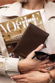 A model wearing the Venice Passport Wallet in colour Chocolate, from the front, showing the whole outfit