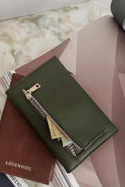 A model wearing the Venice Passport Wallet in colour Olive (Green), from the front, showing the whole outfit