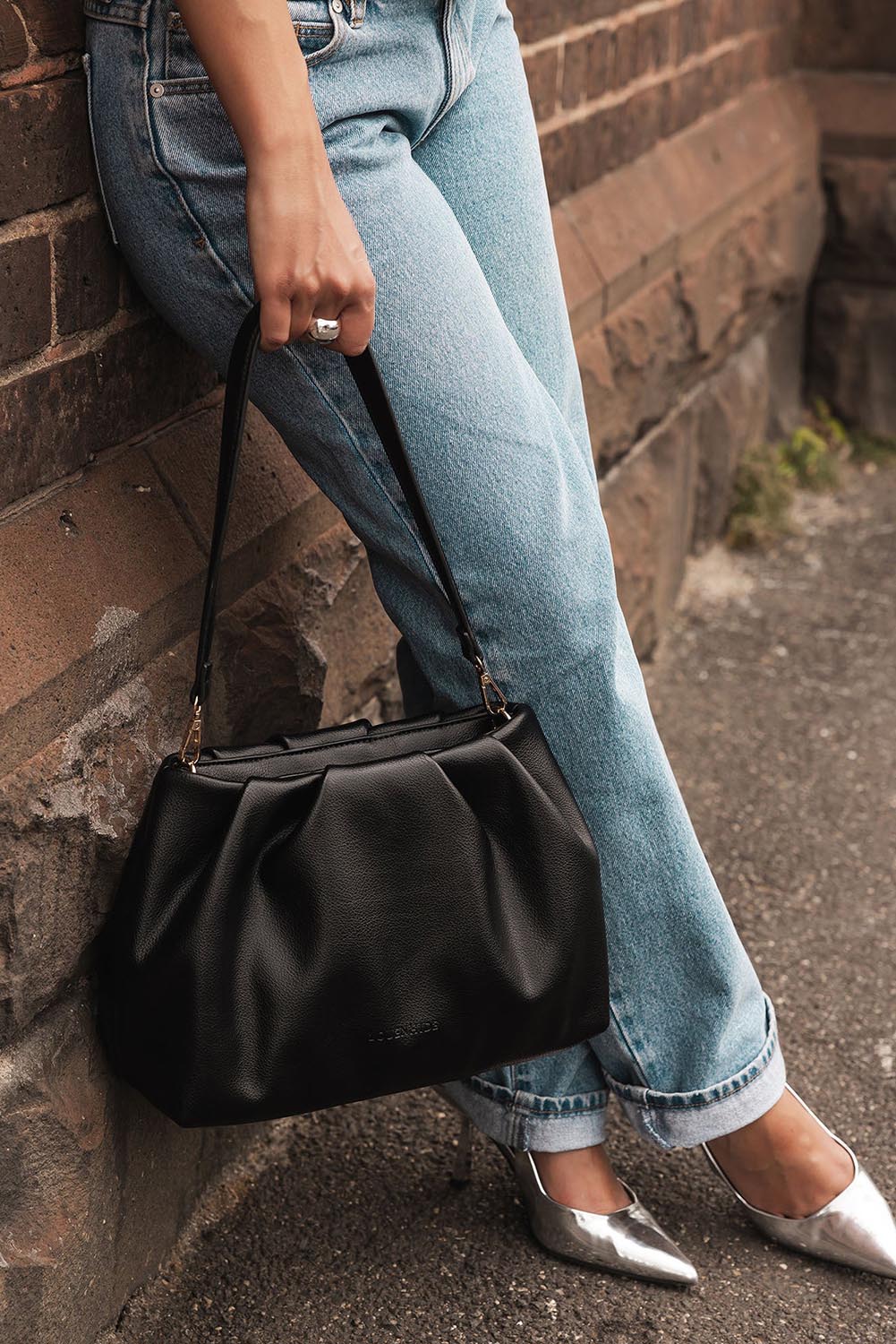 A model wearing the Naomi Convertible Clutch n Shoulder Bag in colour Black (Black), from the front, showing the whole outfit