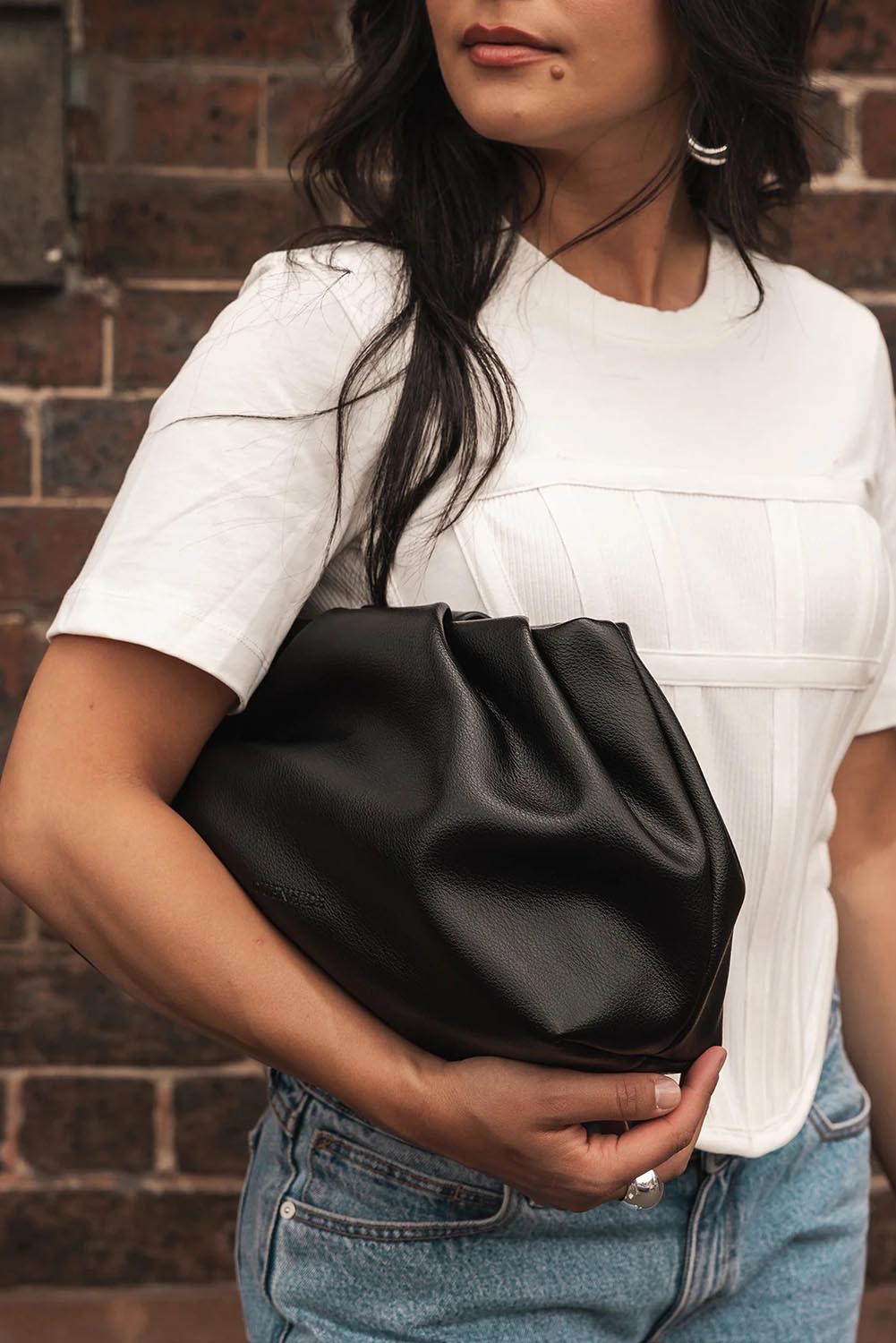 A model wearing the Naomi Convertible Clutch n Shoulder Bag in colour Black (Black), from the front, showing the whole outfit