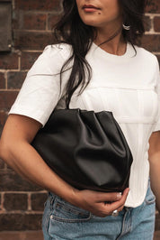 A model wearing the Naomi Convertible Clutch n Shoulder Bag in colour Black (Black), from the front, showing the whole outfit